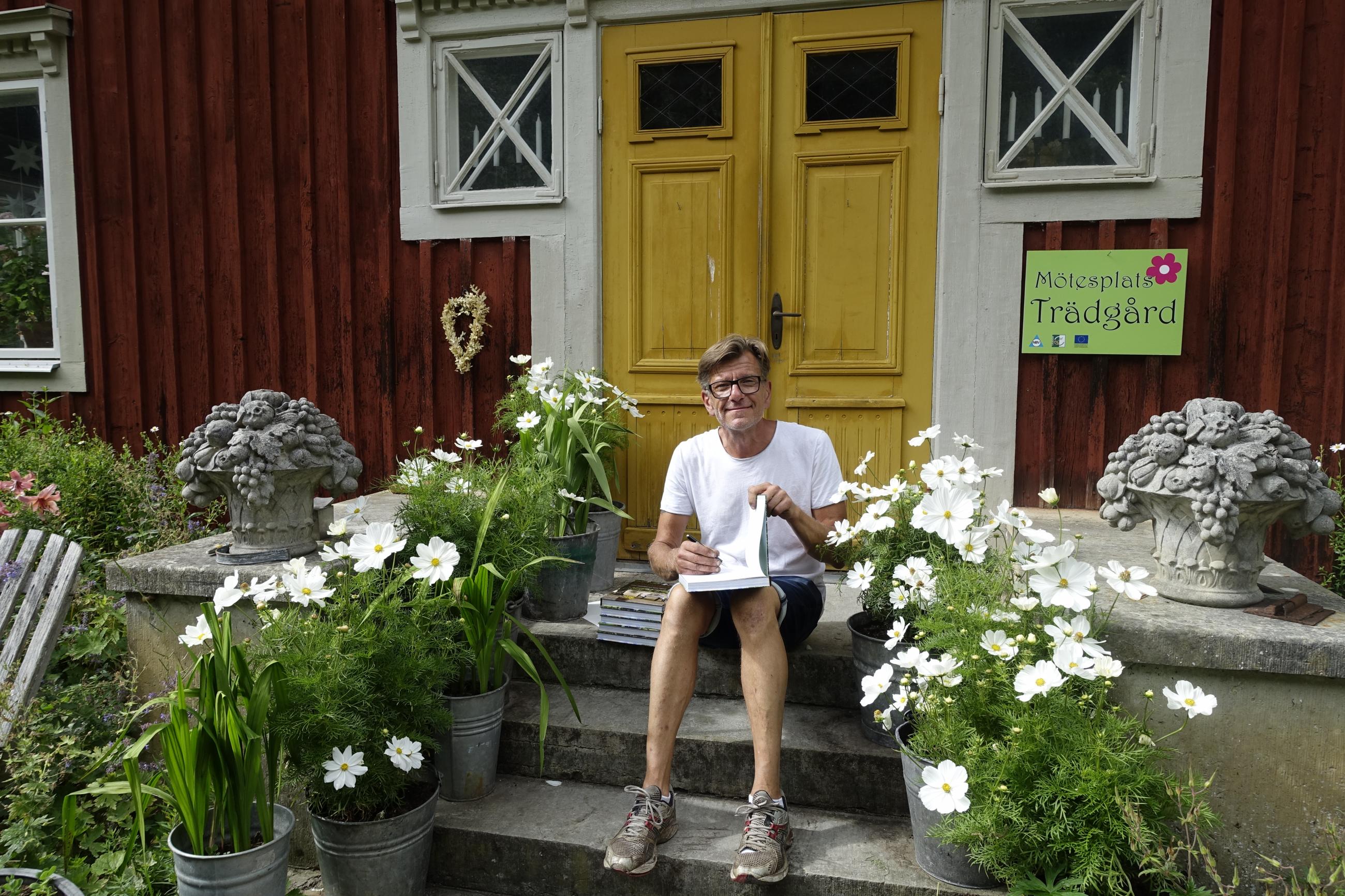 Hannu Sarenström sitter på trappan till sitt hus